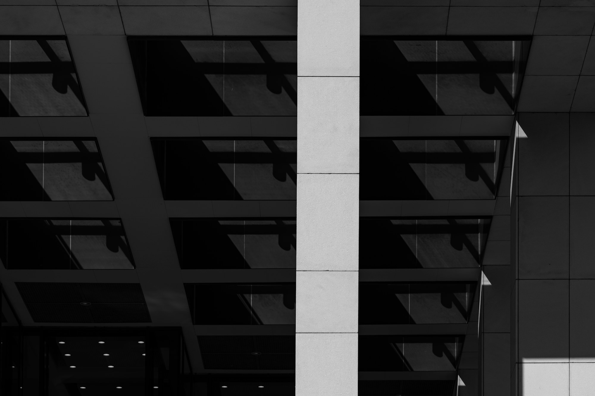 Corporate M&A – architectural hero concept (Declan Sun / Unsplash) Geometric glass facade of a modern commercial building, monochrome architectural detail